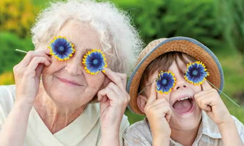 Une personne seniors s'amusant avec un jeune  avec des fleurs à la place des yeux