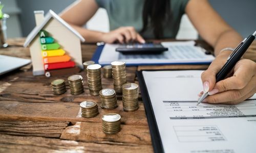 Une femme écrit sur un livre de compte, il y a des pièces de 1 euros empilées