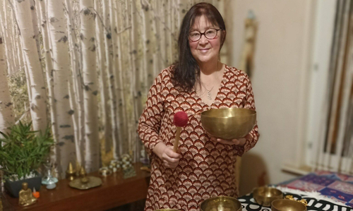 Véronique Debels pratique la sonothérapie, avec des bols dorés dont l'un dans une main et un gong dans l'autre 