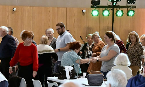 des seniors dansent dans une salle, il y a également. des personnes assises 