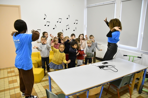 Un groupe d'enfants répond à deux animateurs en teeshirt bleu