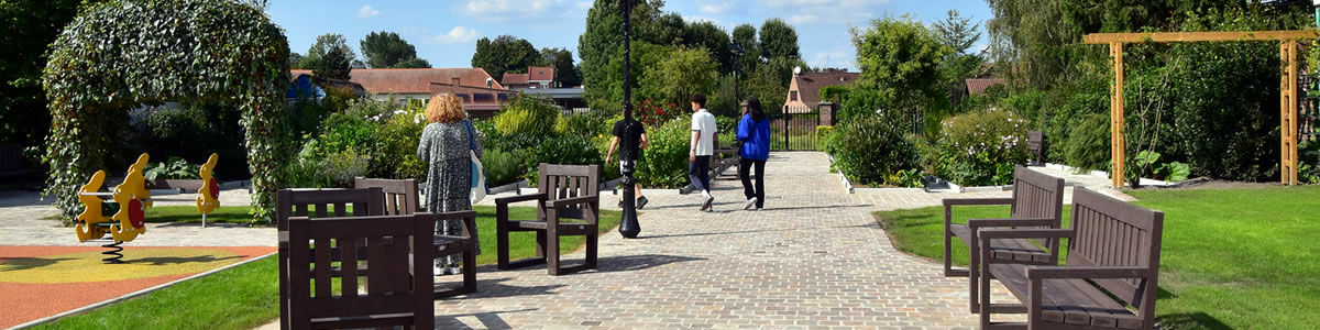 Le jardin des senteurs, un jardin arboré de plantes aromatiques, des bancs en bois bordent une allée en gravier ou des personnes s'y promènent 