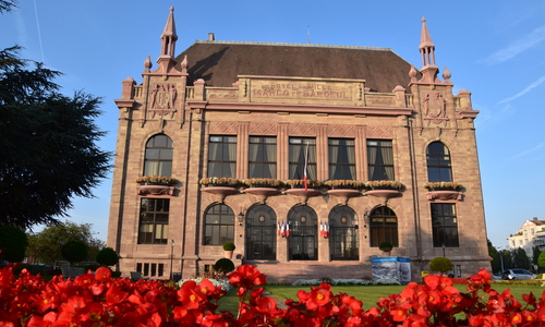 Une vue de l'hotel de ville avec au prmier plan des fleurs rouges