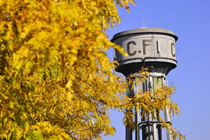 Le château d'eau en béton gris clair marqué avec les inscription CF avec un sur la gauche un arbre d'automne aux feuilles jaunes au premier plan