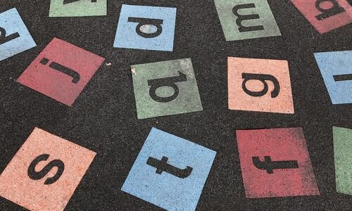 lettres de l'alphabet écrites dans des carrés de couleurs sur le sol
